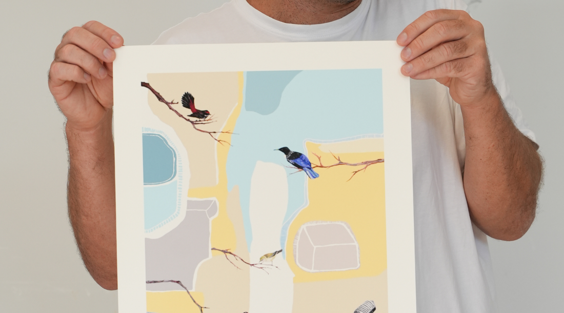 A person in a white t-shirt holds an abstract bird screen print with soft yellow and blue geometric shapes.